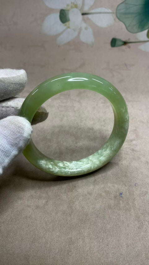 Gelang giok Xiuyan yang indah dengan rona hijau dan tekstur seperti susu, setengah giok dan setengah hijau, diameter dalam: 59,8 mm, lebar tepi: 13 mm. Semua batu terbentuk secara alami. Biaya pengiriman dan pajak sudah termasuk.
