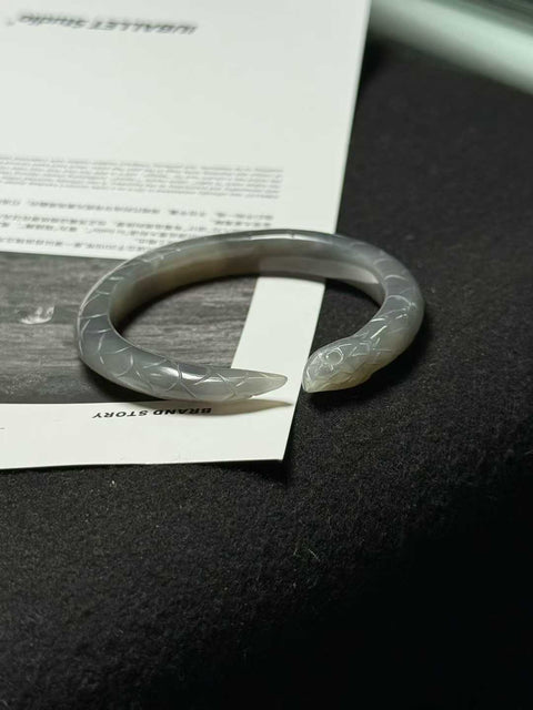 "Gelang ular" giok Hetian biru berasap - tekstur halus dan hangat, diukir tangan hingga tampak seperti aslinya. Ukuran perkiraan: 51 x 9 mm. Semua batu alam terbentuk secara alami; biaya pengiriman dan pajak sudah termasuk.