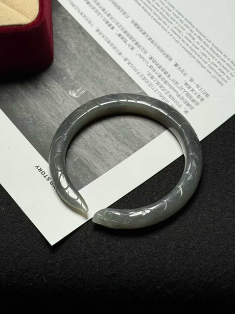 "Gelang ular" giok Hetian biru berasap - tekstur halus dan hangat, diukir tangan hingga tampak seperti aslinya. Ukuran perkiraan: 51 x 9 mm. Semua batu alam terbentuk secara alami; biaya pengiriman dan pajak sudah termasuk.