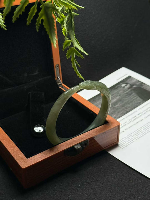 "Gelang Ular" giok Hetian ini memiliki rona hijau danau dan tekstur lembut yang hangat. Desain ukiran tangan yang tampak nyata. Perkiraan dimensi: 58 x 10 mm. Semua barang terbuat dari batu alam; biaya kirim dan pajak sudah termasuk.