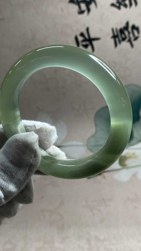 Gelang giok Xiuyan yang indah dengan rona hijau es dan zamrud yang berkilau, melambangkan kekayaan dan kemakmuran seumur hidup. Diameter dalam: 55,6 mm, lebar samping: 12,3 mm. Semua batu terbentuk secara alami. Biaya pengiriman dan pajak sudah termasuk.