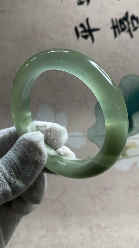 Gelang giok Xiuyan yang indah dengan rona hijau es dan zamrud yang berkilau, melambangkan kekayaan dan kemakmuran seumur hidup. Diameter dalam: 55,6 mm, lebar samping: 12,3 mm. Semua batu terbentuk secara alami. Biaya pengiriman dan pajak sudah termasuk.