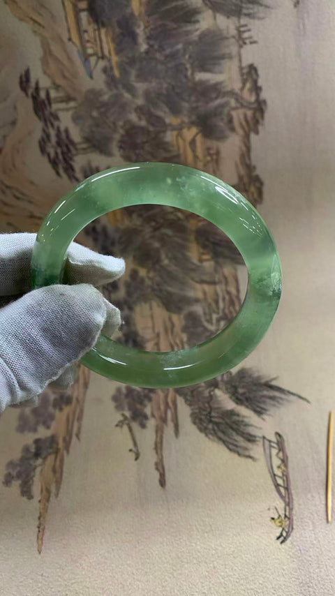 Gelang giok Xiuyan yang indah, berwarna hijau es dengan zamrud yang mengambang, melambangkan kekayaan dan kemakmuran seumur hidup. Diameter dalam: 58 mm, lebar tepi: 12,6 mm. Semua batu terbentuk secara alami. Biaya pengiriman dan pajak sudah termasuk.