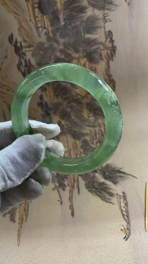 Gelang giok Xiuyan yang indah, berwarna hijau es dengan zamrud yang mengambang, melambangkan kekayaan dan kemakmuran seumur hidup. Diameter dalam: 58 mm, lebar tepi: 12,6 mm. Semua batu terbentuk secara alami. Biaya pengiriman dan pajak sudah termasuk.