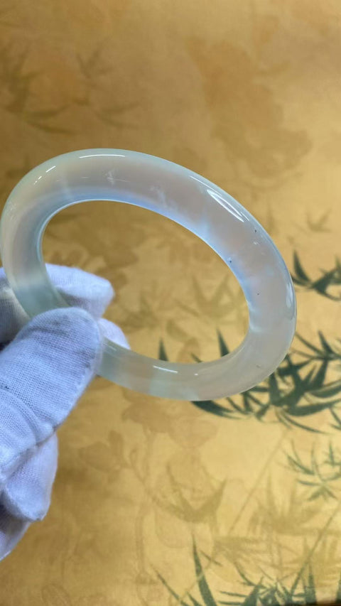 Gelang tangan berbentuk lingkaran tebal dari batu giok Xiu Yu jenis es, transparan seperti es, bulat dan halus, diameter 56,8 mm, ketebalan 10,3 mm. Batu alam ini terbentuk secara alami, pola dan coraknya acak. Termasuk biaya pengiriman dan pajak.