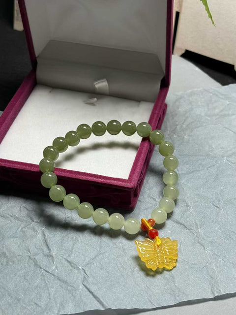 Gelang "Lucky Butterfly Bracelet" dari giok Hetian dengan gradasi hijau dan kupu-kupu amber, ukuran sekitar 8mm. Harga sudah termasuk ongkos kirim dan pajak.
