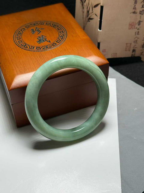 Gelang giok Xiuyan, berwarna hijau kacang dan krem, dengan jimat keberuntungan, berukuran sekitar 54mm. Semua batu terbentuk secara alami. Harga sudah termasuk ongkos kirim dan pajak.