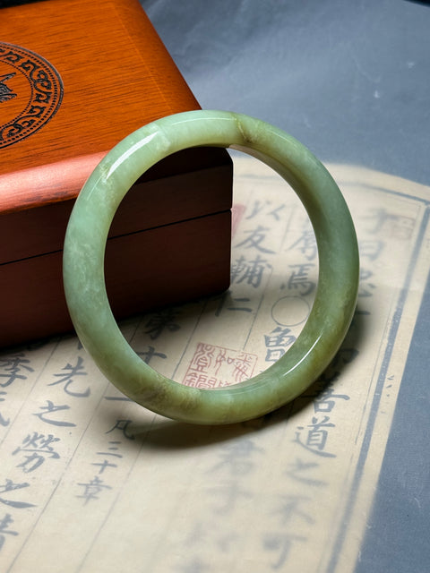 Gelang giok Xiuyan alami, dihiasi dengan desain yang disebut "Kekayaan Tak Tertandingi." Perkiraan dimensi: 62×13×8,9 mm. Semua batu terbentuk secara alami; termasuk ongkos kirim dan pajak.