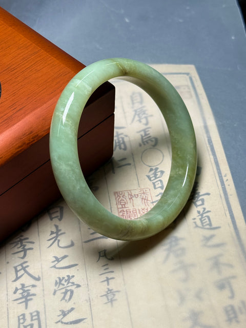 Gelang giok Xiuyan alami, dihiasi dengan desain yang disebut "Kekayaan Tak Tertandingi." Perkiraan dimensi: 62×13×8,9 mm. Semua batu terbentuk secara alami; termasuk ongkos kirim dan pajak.