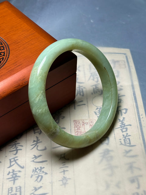Gelang giok Xiuyan alami, dihiasi dengan desain yang disebut "Kekayaan Tak Tertandingi." Perkiraan dimensi: 62×13×8,9 mm. Semua batu terbentuk secara alami; termasuk ongkos kirim dan pajak.
