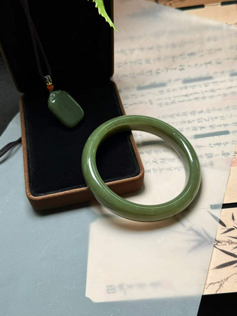 Giok Hetian dengan tekstur kuning kehijauan, meningkatkan keputihan dan keanggunan. Set dua buah, perkiraan dimensi: Diameter dalam gelang 55-62mm, Liontin 28×19mm.