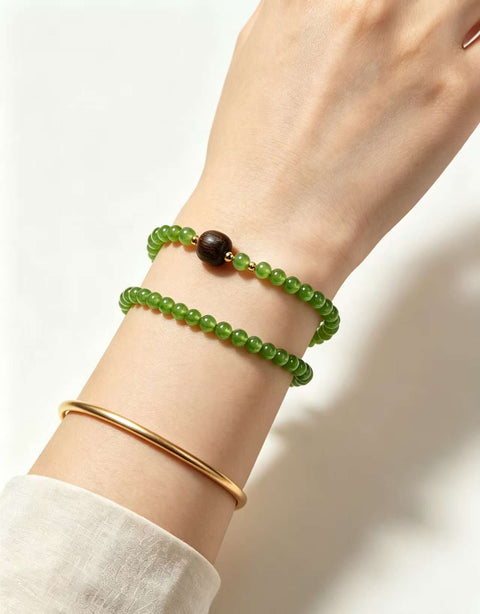 Gelang giok Hetian ini memiliki warna hijau hangat dan berkilau, serta dihiasi dengan aksen kayu gaharu. Desainnya yang sederhana membuatnya cocok untuk berbagai kesempatan. Ukuran perkiraan: 4 mm. Harga sudah termasuk ongkos kirim dan pajak.