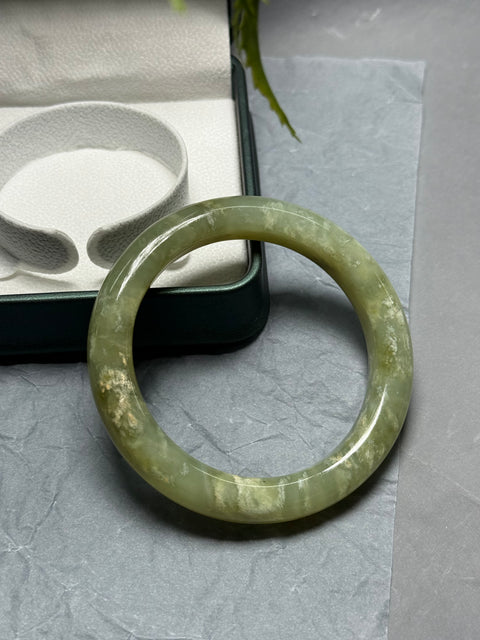 Gelang giok Xiuyan alami, dihiasi dengan desain bunga yang halus dan elegan. Perkiraan dimensi: 58,2 x 12 x 10 mm. Semua batu terbentuk secara alami. Harga sudah termasuk ongkos kirim dan pajak.
