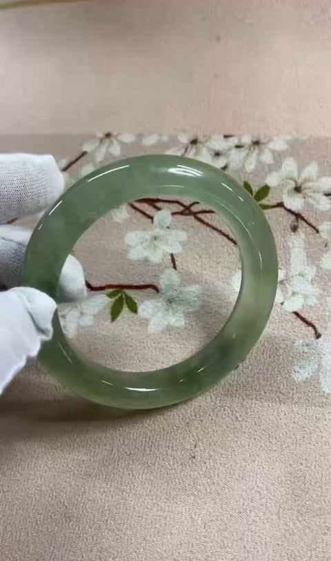 Gelang giok Xiuyan yang indah, dengan semburat hijau yang mengambang di dalamnya. Diameter dalam: 60,5 mm, lebar samping: 11,8 mm. Batunya terbentuk secara alami; polanya acak. Biaya pengiriman dan pajak sudah termasuk.